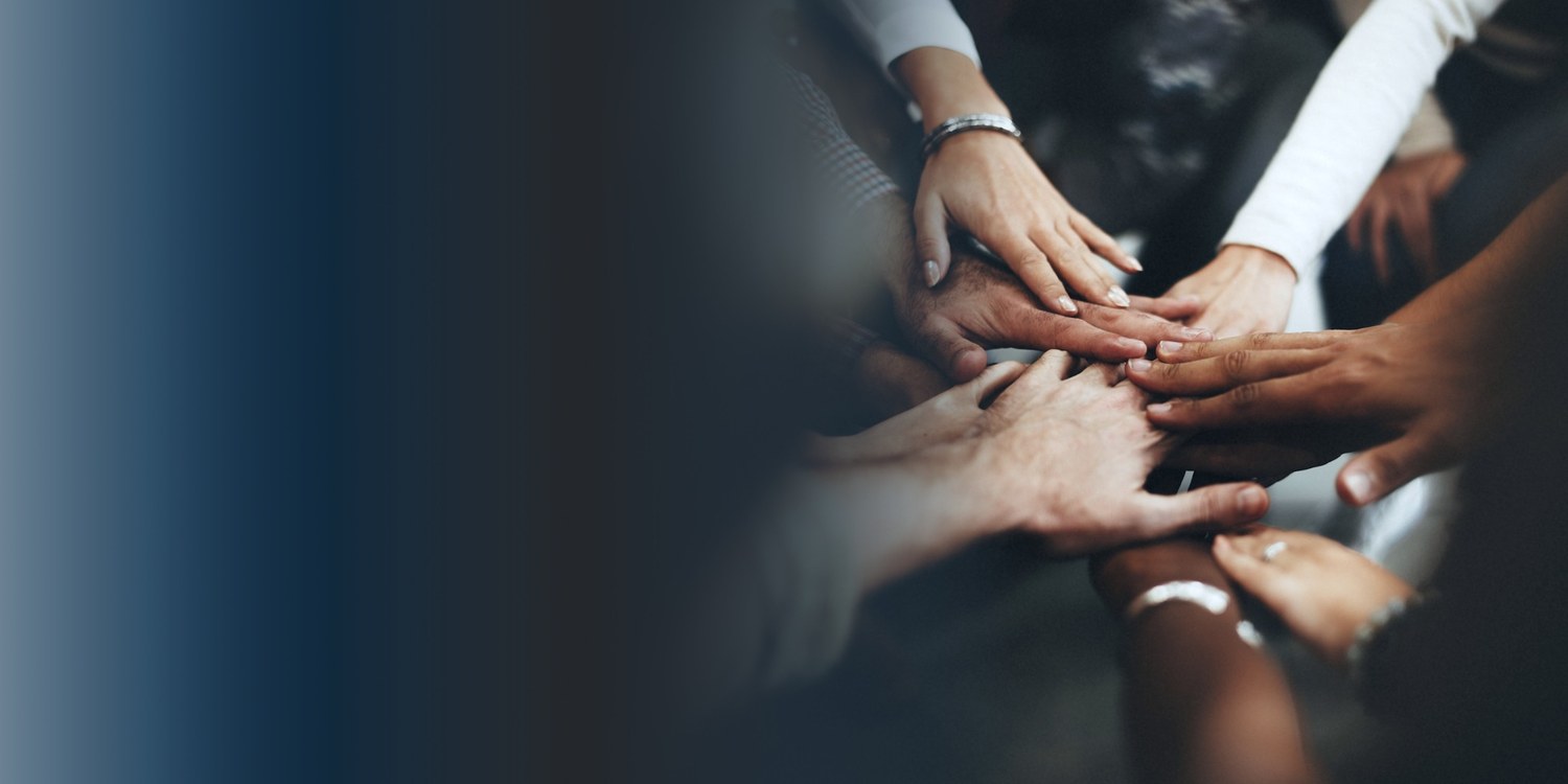 Manos de un equipo reunidas como símbolo de colaboración e inclusión